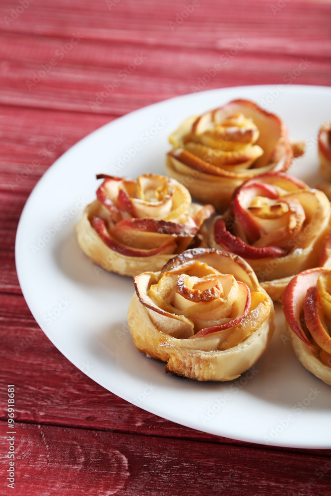 Fresh puff pastry with apple shaped roses on red wooden table