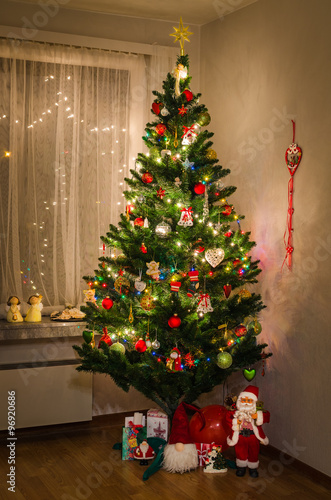 Decorated Christmas tree with Santa and gifts in interior