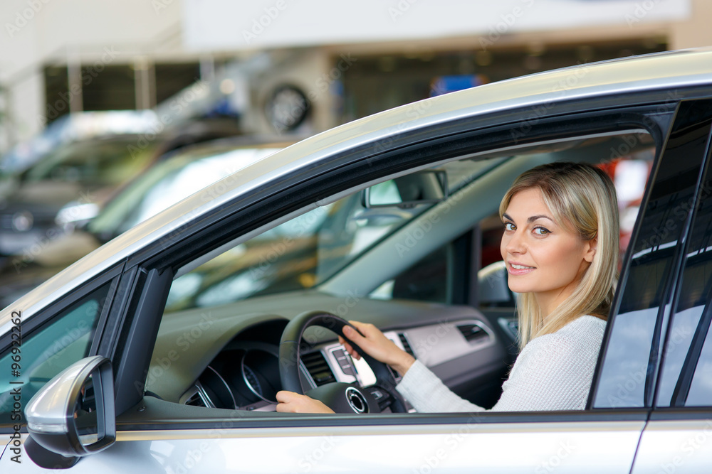 Nice woman choosing a car in auto show 