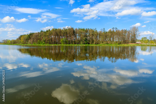 Reflection of clouds in water of a lake and trees in background - idyllic scenic landscape view, Poland