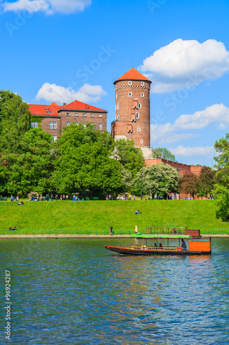 Tourist boat on Vistula river with Wawel Royal Castle in the background on sunny beautiful day, Poland