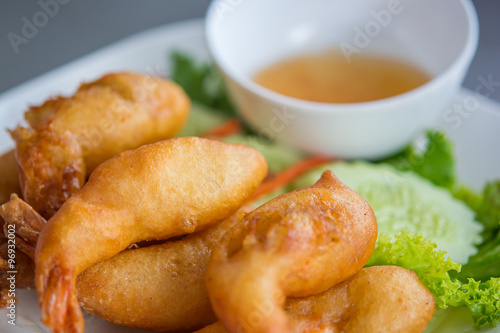 Batter fried prawns with plum sauce and vegetable, on a white pl