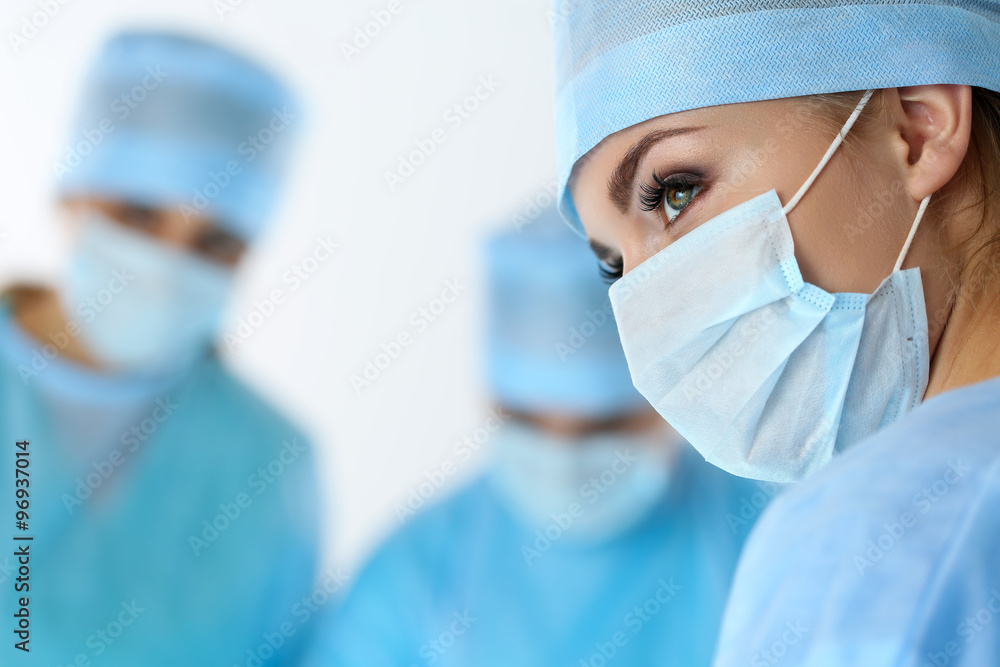 Three surgeons at work operating in surgical theatre saving pati Three surgeons at work operating in surgical theatre saving pati