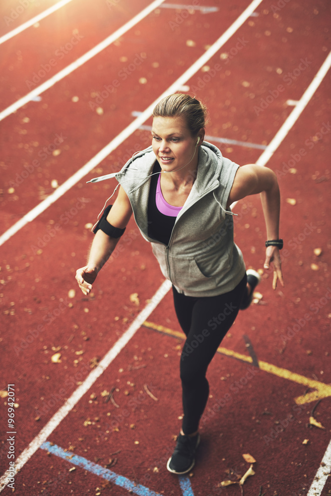 Obraz premium Athletic young woman running on track field
