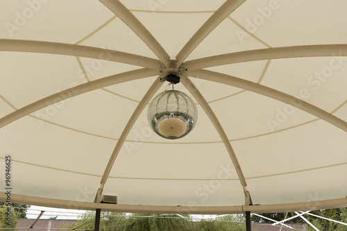 A mosaic ball in a tent with some trees in the background 