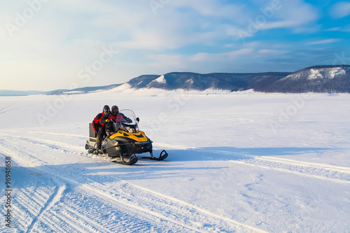 people driving snowmobile in winter mountain 