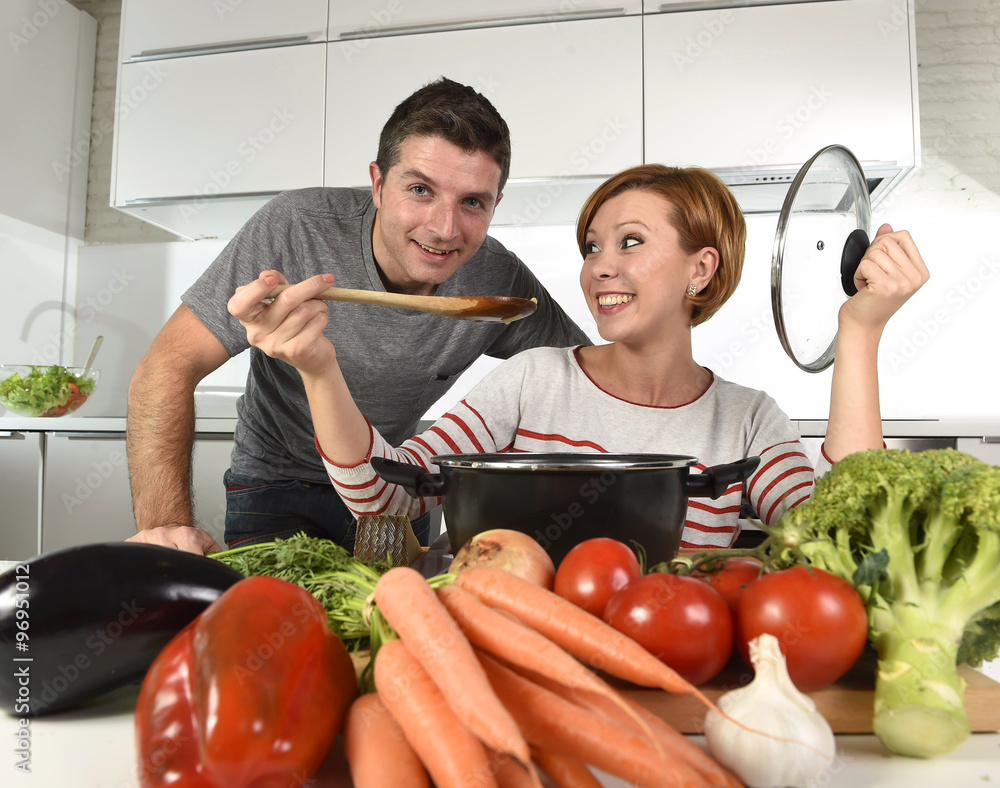 young attractive couple at home kitchen with man tasting vegetable stew cooked by her wife smiling happy young attractive couple at home kitchen with man tasting vegetable stew cooked by her wife smiling happy