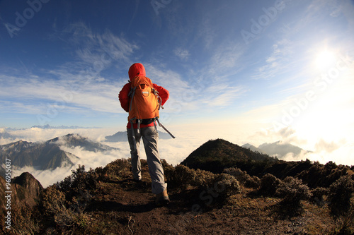  young woman backpacker hiking to beautiful mountain peak