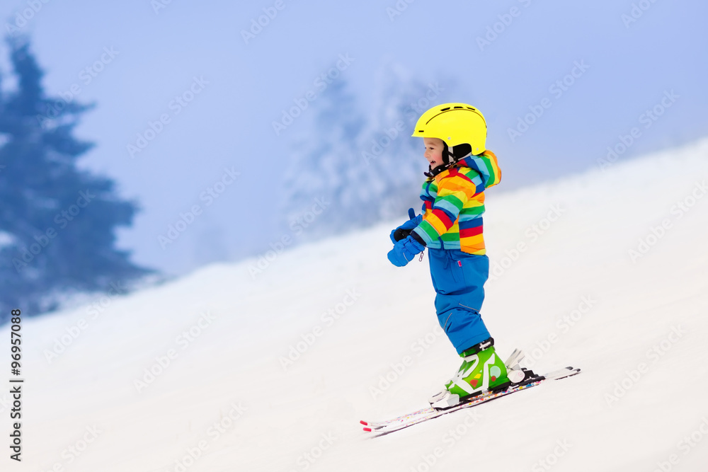 Little child skiing in the mountains in winter