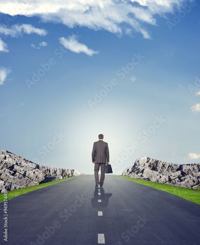 Businessman in suit on road with mountains