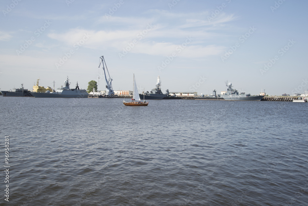Маленькая яхта на фоне военных кораблей. Петровская гавань, Кронштадт