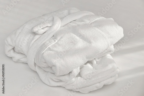 White Folded Bathrobe On The Bed Sheet