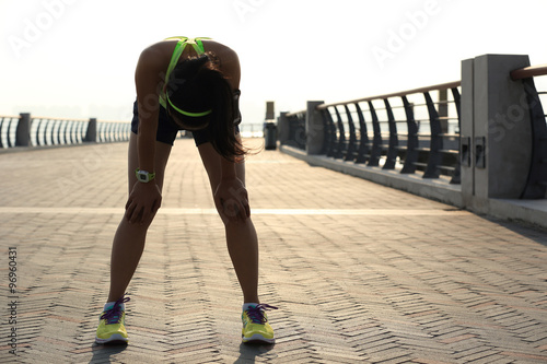 Obraz na plátně tired woman runner taking a rest after running hard on sunshine seaside