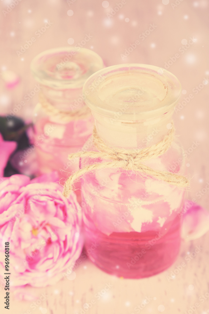 Rose oil in bottles on light background Rose oil in bottles on light background