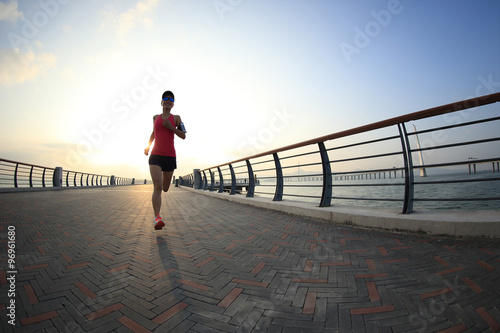 young woman runner tying shoelace  at the sunrise seaside