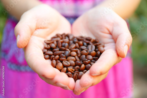 Woman holds in hands roasted coffee beans, heart shaped