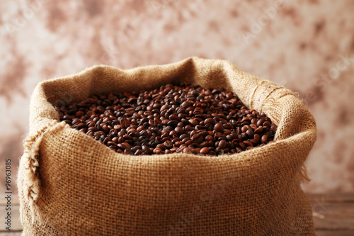 Sac with roasted coffee beans on light-brown background