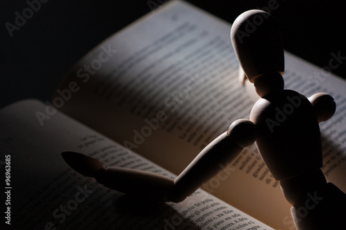 Cuadro en lienzo Wooden puppet reading a book