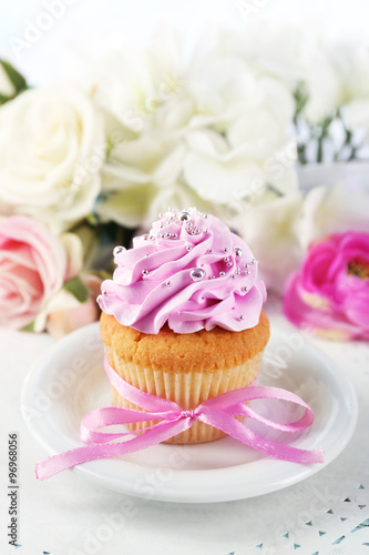 Tasty cupcake on plate, on light background