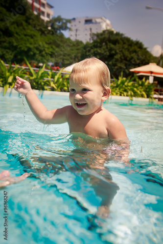 closeup small blonde girl smiles looks into water in pool © SlavaStock