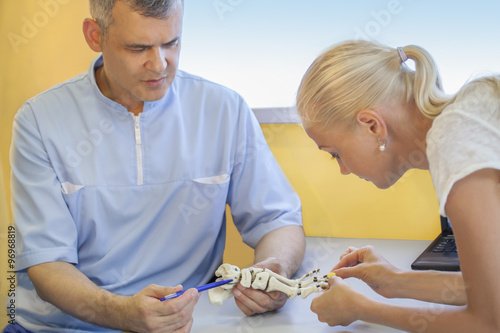 0rthopedist doctor in his office with patient and model of foot