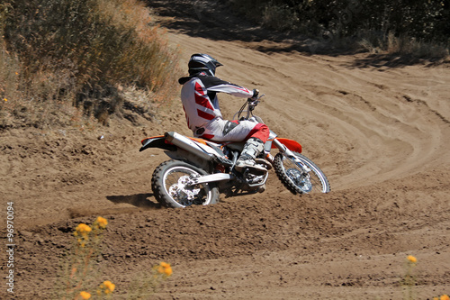 MX rider on a motorcycle rides cornering along the sandy furrow motocross track