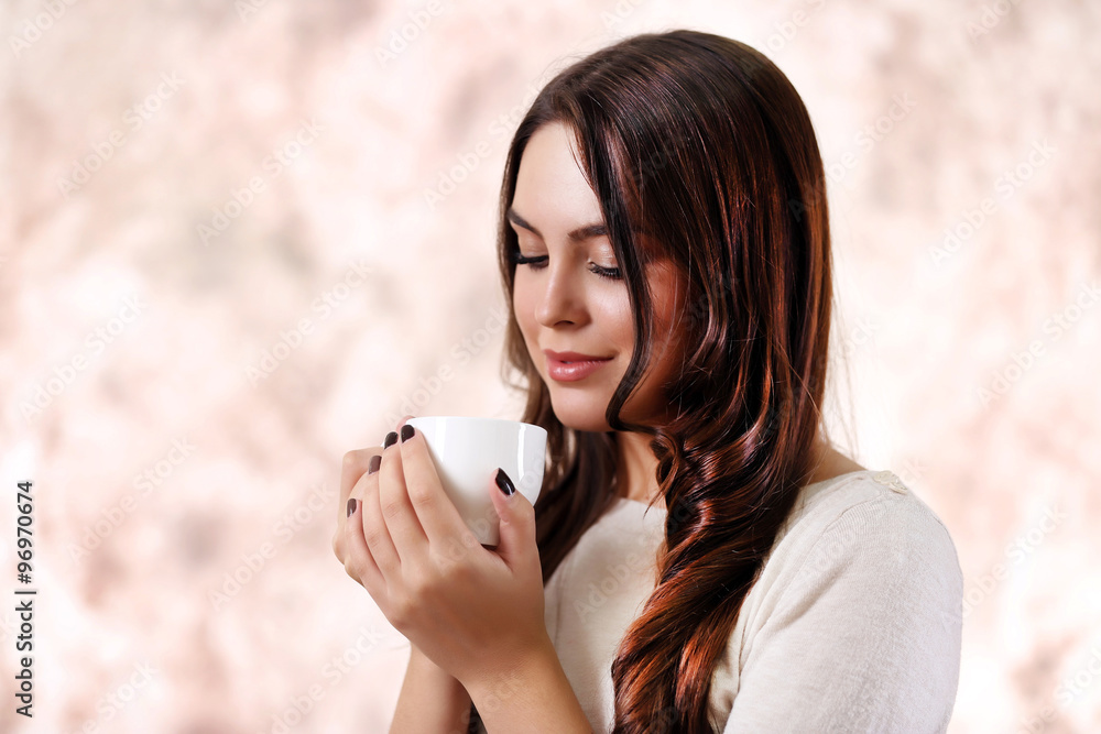 Portrait of smiling pretty woman with cup of coffee on pink blurred background Portrait of smiling pretty woman with cup of coffee on pink blurred background