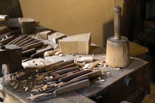 Eine Arbeitsbank eines Schnitzlers mit Hammer und Meisseln und Holzresten.