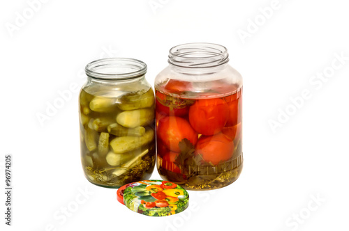 canned cucumbers and tomatoes in glass jars on white