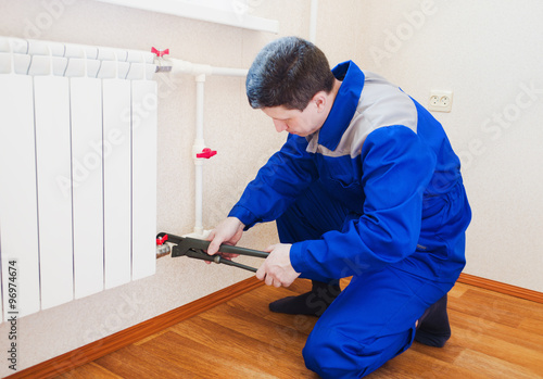 A plumber performs the installation of radiator heating