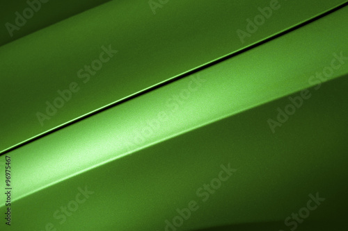 Surface of green sport sedan car, detail of metal hood and fender of vehicle bodywork