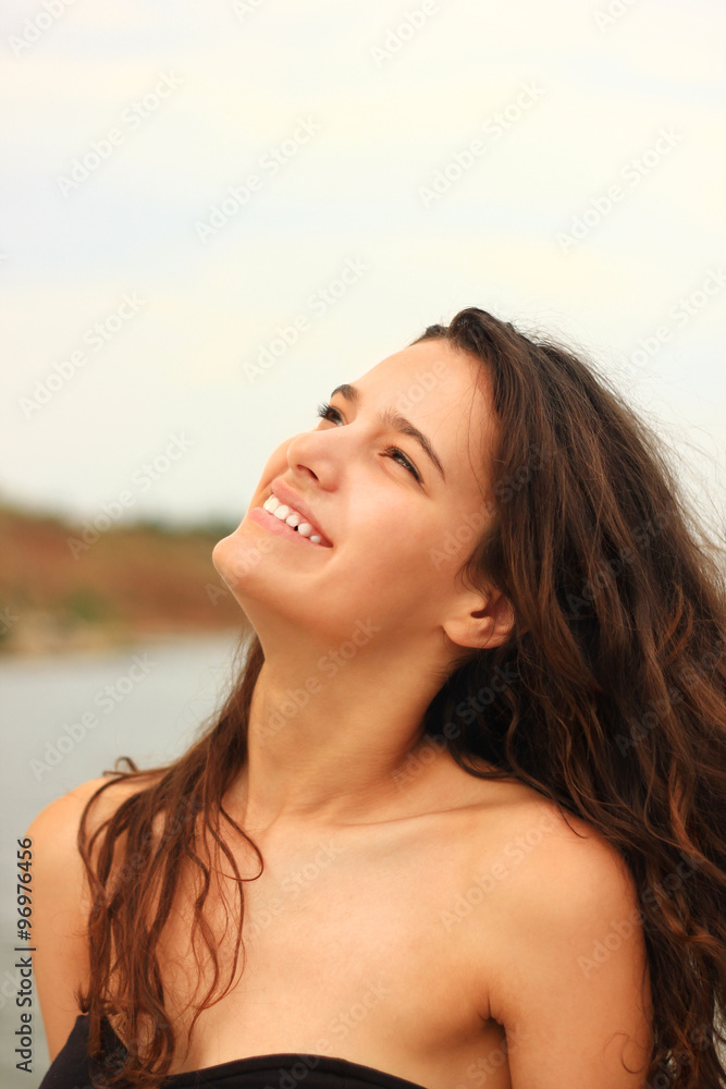 Beautiful slim brunette girl model posing in fashion dress by the sea, outdoor portrait
