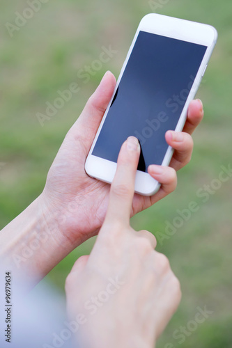 Closeup of female hand using a mobile phone on farm background