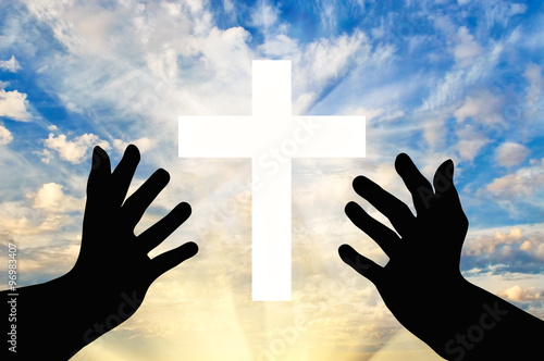 Silhouette of praying hands and a cross