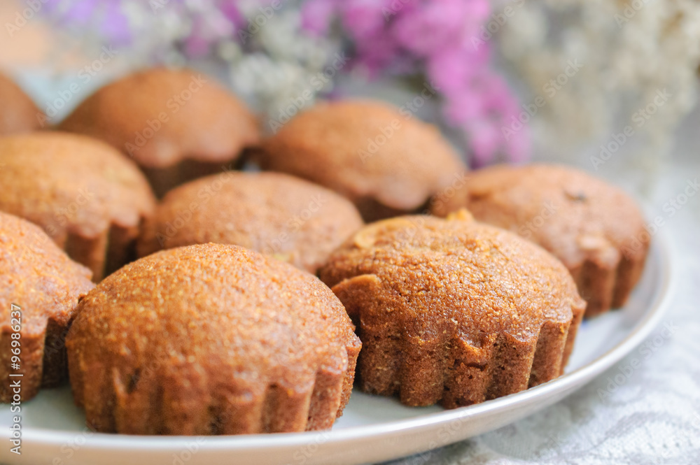 Many  small sweet honey muffins on a white plate, selective focus 