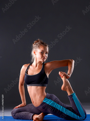 Young woman doing yoga exercise on gray background #96987689