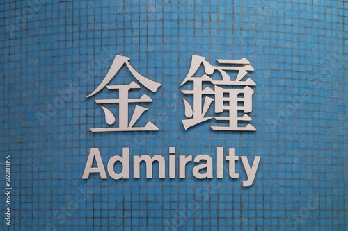 Sign of Admiralty MTR (subway/metro) station in Hong Kong, China, written in Chinese and English on small blue tile wall, viewed from the front. photo