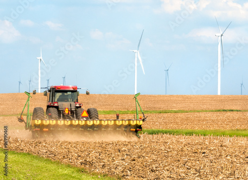 Farmer seeding soybeans in tractor in field near wind farm in Danville Illinois Midwest USA
