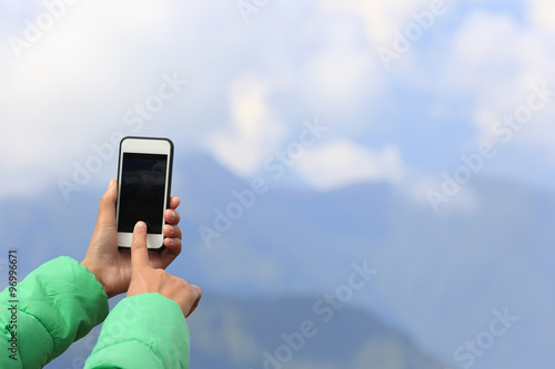 woman hands taking photo with smart phone on mountain peak photo