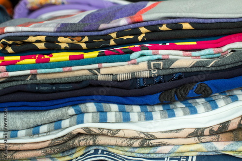 Men's T-shirts are piled up in a closet. Wearing these colorful shirts can make the day cheerful.