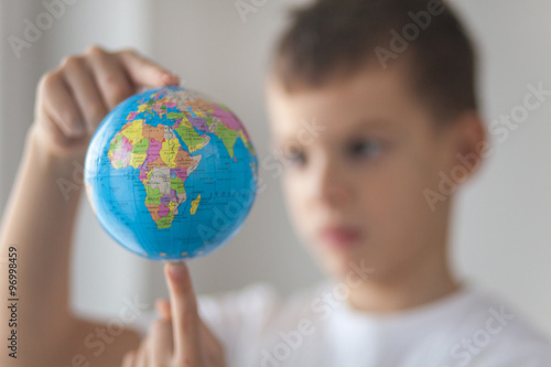 Fotografie Boy holding toy globus in his hand. Day natural window light