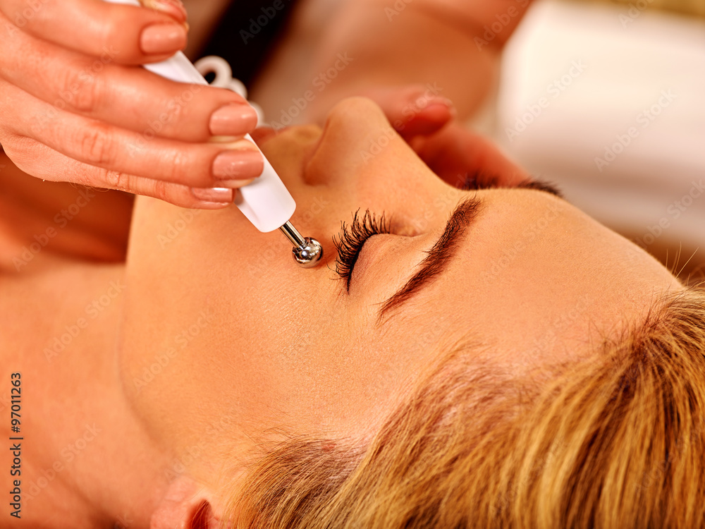 Young woman receiving electric facial massage.