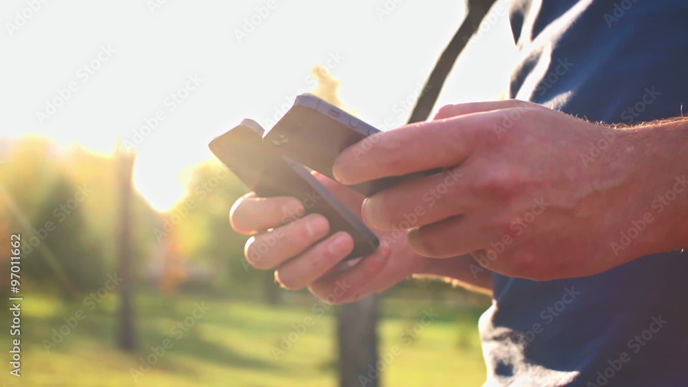 Close-up of man holding and using smartphones in both hands Close-up of man holding and using smartphones in both hands