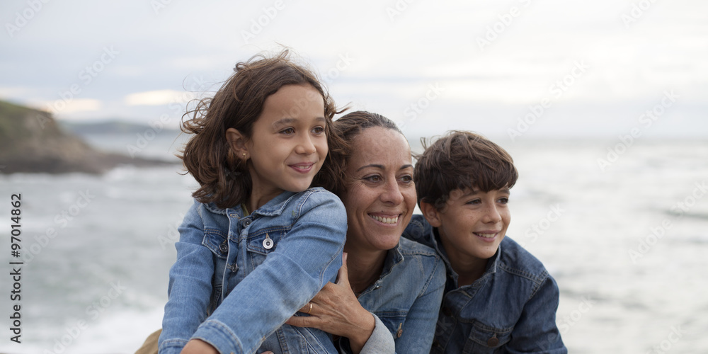 Madre, hijo e hija sonriendo mirando al mar