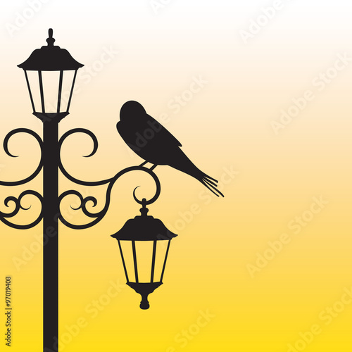 Silhouette of bird sitting on lamppost