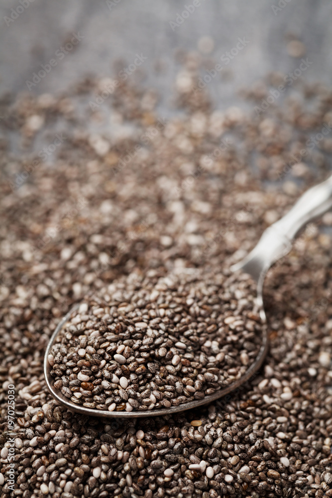 Chia seeds in silver spoon on black table, shallow depth of field Chia seeds in silver spoon on black table, shallow depth of field