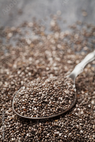 Chia seeds in silver spoon on black table, shallow depth of field