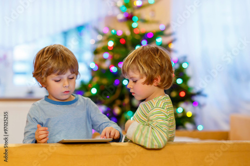 Two happy little kids playing with tablet pc, indoors