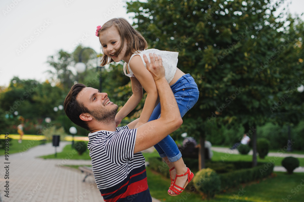 Happy family Dad throws child daughter up on a walk  in park