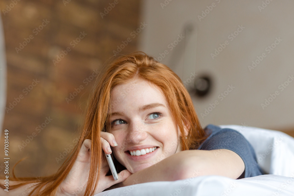 Fototapeta premium Woman talking on the phone in bed